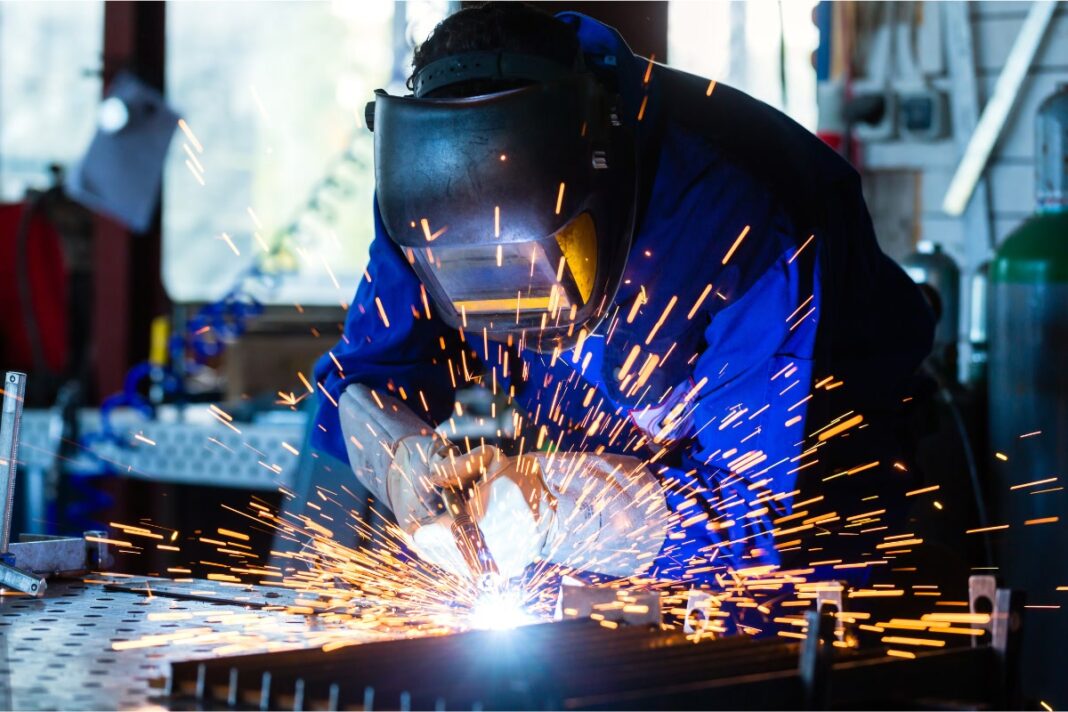 Trabajador suelda metales en un taller.